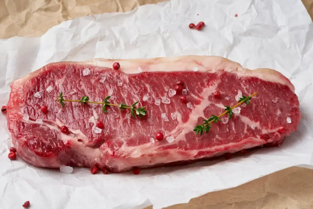 preparing raw beef sirloin on a parchment paper to be cooked in the air fryer