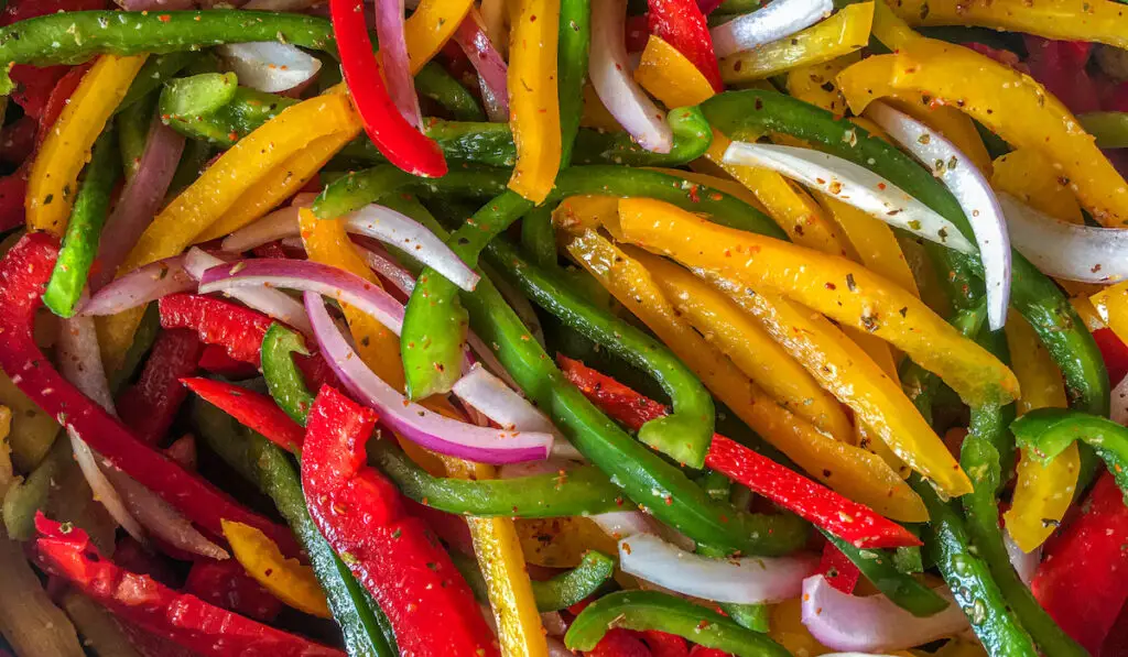 Sliced yellow, green and red bell peppers and onions 